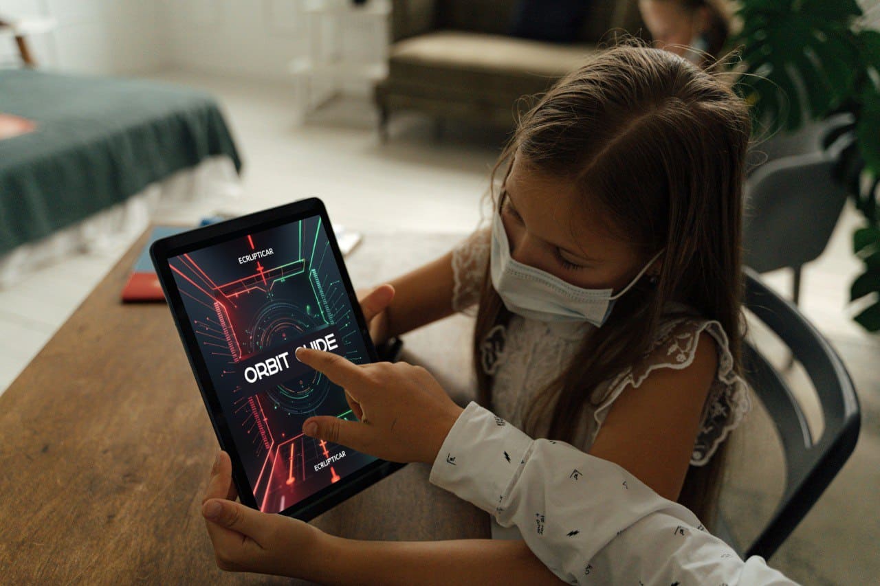 Child using a tablet with a 'Orbit Guide' course display in a home setting